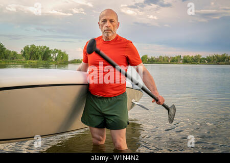 Portrait de l'environnement d'un pagayeur senior avec son stand up paddleboard sur un lac dans le Colorado. Banque D'Images