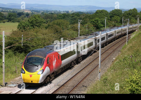 La côte ouest de la classe en livrée vierge 390 Pendolino électriques avec express train de passagers en campagne West Coast Main Line 3 juillet 2019. Banque D'Images
