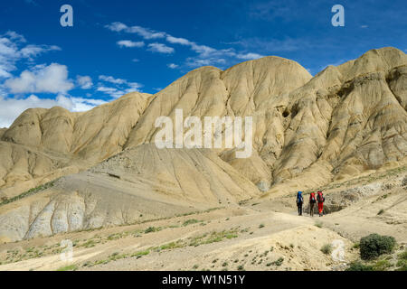 Trois marcheurs, randonneurs dans le typique paysage surréaliste pour Mustang dans le désert autour de la haute vallée de la Kali Gandaki, la plus profonde vallée au monde Banque D'Images