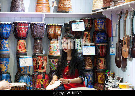 Jeune fille asiatique jouant sur tambour bongo, vieille ville de Lijiang en Chine. Banque D'Images