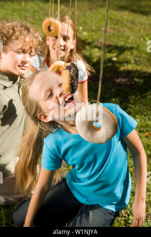 Enfants jouant donut capture, des anniversaires Banque D'Images