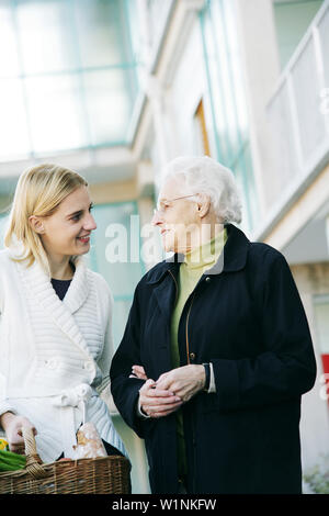 Jeune femme aide une dame âgée et porte le shopping Banque D'Images