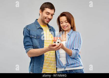 Smiling couple holding model house Banque D'Images