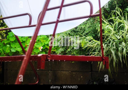 Metal swing dans la cour après une averse. L'eau de pluie remplit l'auvent blanc du soleil Banque D'Images