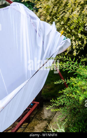 Metal swing dans la cour après une averse. L'eau de pluie remplit l'auvent blanc du soleil Banque D'Images