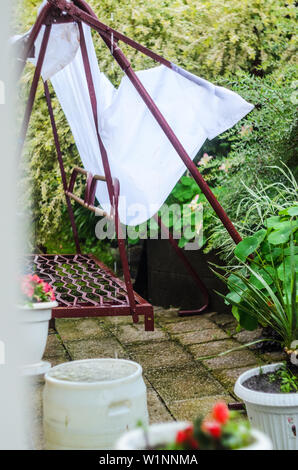 Metal swing dans la cour après une averse. L'eau de pluie remplit l'auvent blanc du soleil Banque D'Images