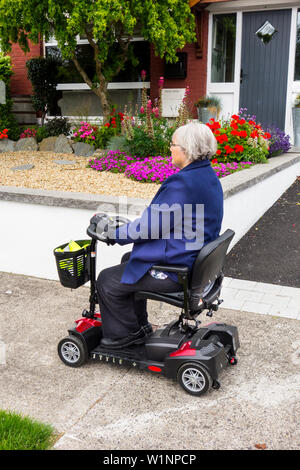 Une femme plus âgée voyageant sur un scooter de mobilité Banque D'Images