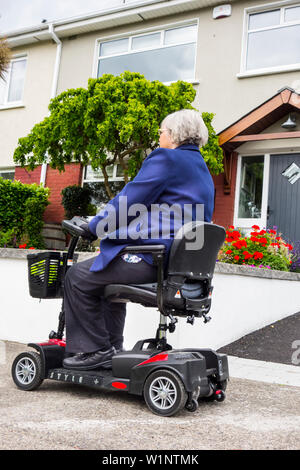 Une femme plus âgée voyageant sur un scooter de mobilité Banque D'Images
