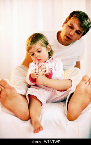 Little girl holding son pied Banque D'Images