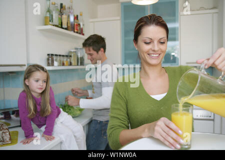 Jeune femme de servir un verre de jus, man and girl en arrière-plan, Munich, Allemagne Banque D'Images