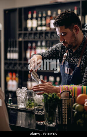 Bartender pouring Ice Cube en verre - préparer mojito cocktail Banque D'Images
