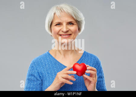 Smiling senior woman with red heart Banque D'Images