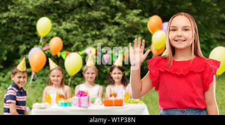 Smiling girl waving hand at Birthday party in park Banque D'Images