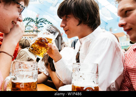 Jeune homme en tissu traditionnel de la consommation de bière dans la bière tente à l'Oktoberfest, Munich, Bavière, Allemagne Banque D'Images