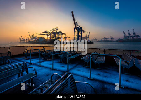 Lever du soleil, un jour d'hiver dans le port de Hambourg au container terminal Burchardkai vu depuis le ferry de l'Elbe, Hambourg, Allemagne Banque D'Images