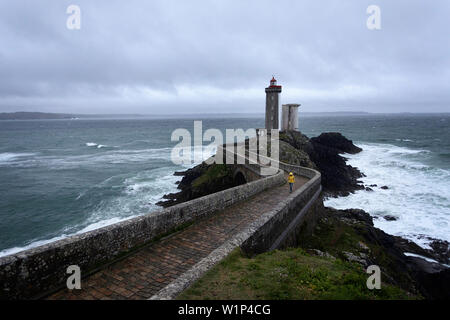 Femme en imperméable jaune marche sur le pont à Phare du petit minou, Plouzané, Brest, Finistère département, Bretagne - Bretagne, France, Europe Banque D'Images