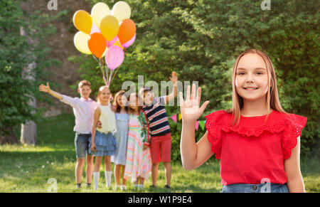 Smiling girl waving hand at Birthday party in park Banque D'Images