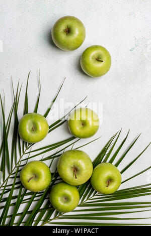 La pomme verte avec des feuilles tropicales sur fond blanc. Concept d'une alimentation saine en toile de fond. Mise à plat, vue du dessus Banque D'Images