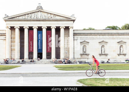 Jeune femme en face de la bicyclette sur Glyptothèque Königs Plaza à Munich, Bavière, Allemagne Banque D'Images