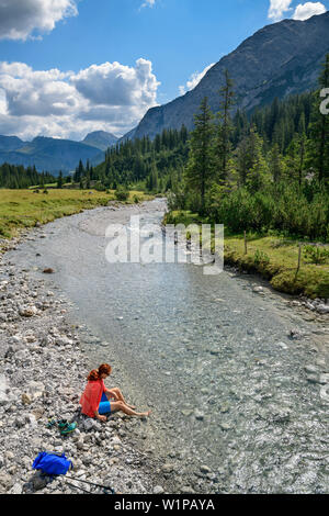 L'Lechweg randonnées femme baigne, pieds dans la Lech, Lech montagnes source, Vorarlberg, Autriche Banque D'Images