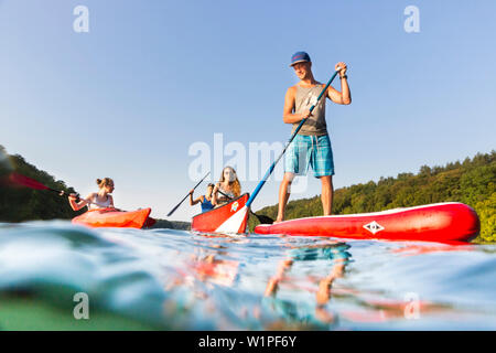 Stand up Paddling, sur le lac, avec palettes de garçon rouge, SUP, in red voile, canot, kayak, sports nautiques, clair comme de l'eau verte, lac Schmaler Luzin, ho Banque D'Images