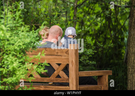 Père et deux enfants assis sur un banc dans le jardin, maison de vacances, vacances, été, Spreewald, Oberspreewald, Brandenburg, Allemagne Banque D'Images