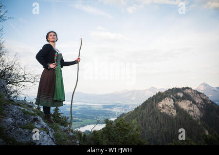 Jeune femme en costume traditionnel debout sur un rocher sur le Falkenstein dans l'Allgaeu, Pfronten, Bavière, Allemagne Banque D'Images