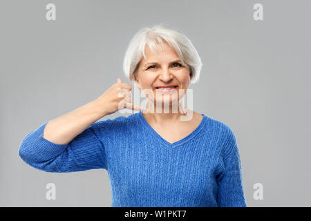 Smiling senior woman making phone geste d'appel Banque D'Images