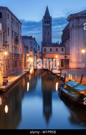 Maisons illuminées du Rio di San Barnaba avec la tour de l'église de Santa Maria dei Carmini et bateaux dans le bleu crépuscule, Dorsoduro, Venise, Ve Banque D'Images