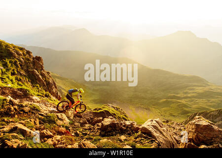 Middle aged mountainbiker monte un chemin technique sur un éperon rocheux en pente chaud belle lumière du matin, Kirchberg, dans le Tyrol, Autriche Banque D'Images