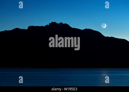 Feux arrière voiture comme baguettes lumineuses à l'avant du sur le lac de Chiemsee Kampenwand, la lune brille Banque D'Images