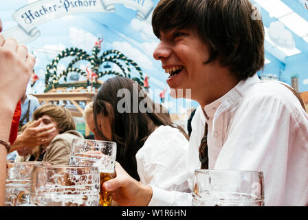 Young laughing man en tissu traditionnel dans la bière tente à l'Oktoberfest, Munich, Bavière, Allemagne Banque D'Images