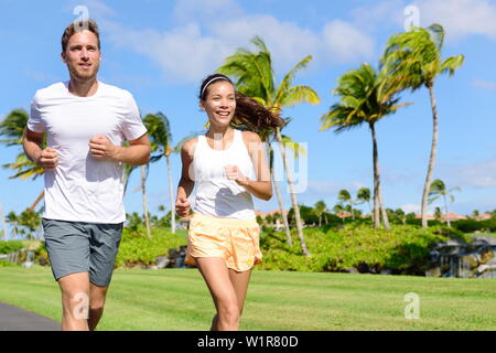 Les personnes en cours d'exécution dans city park. Happy young couple vivant une vie saine et active la formation de leur jogging cardio pendant l'été sur la route ou la rue de quartier. Groupe multiracial, asiatique et caucasienne. Banque D'Images