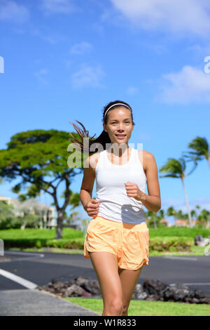 Young woman jogging on city street en été. Asian girl faisant de l'exercice cardio training le corps à perdre du poids et rester en forme et en forme. Portrait taille de female jogger pour aller courir. Banque D'Images