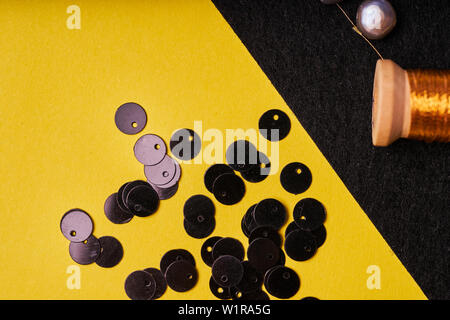 Produits et outils de broderie. Avec la bobine de fils métalliques, perles et paillettes sur noir feutre. Banque D'Images