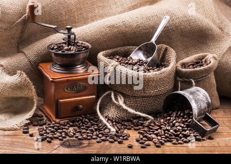 Les grains de café en sac de jute avec un moulin à café en bois Banque D'Images