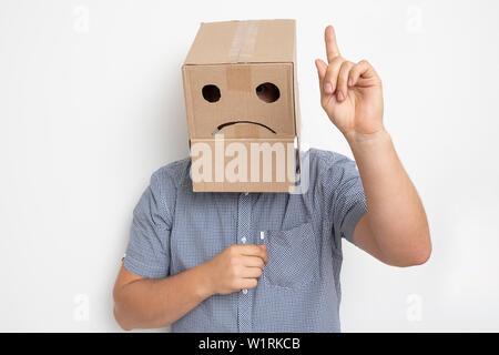 Description : un homme avec une boîte en carton sur la tête, un smiley triste Banque D'Images