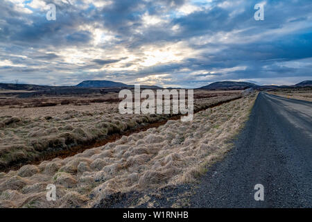 Route de gravier longue par le Cercle d'or du centre de l'Islande avec des montagnes au loin Banque D'Images