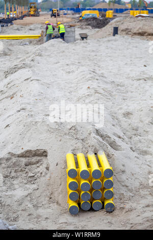 Les tuyaux en PVC jaune pour les systèmes de câble enterré dans le sable. Les tuyaux en polyéthylène sont utilisés comme des canaux de câbles optiques et de fournir une protection pour les télécommunications Banque D'Images