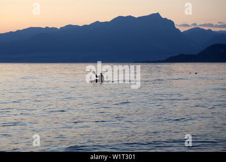 Rameur solitaire sur le lac au coucher du soleil Banque D'Images