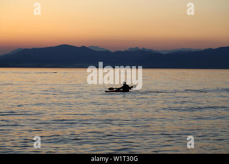 Rameur solitaire sur le lac au coucher du soleil Banque D'Images