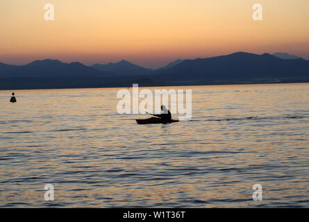 Rameur solitaire sur le lac au coucher du soleil Banque D'Images