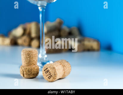 Un verre de vin vide sur un fond bleu se trouve sur un tableau blanc. Bouchons de bouteilles de vin de près. Cher dégustation vin. Banque D'Images