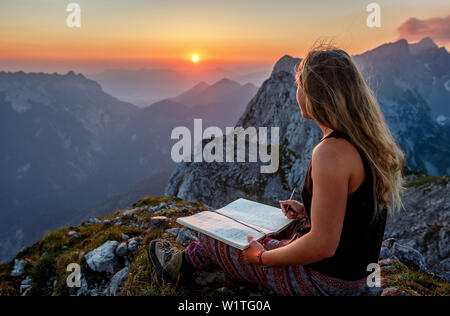 Jeune femme au sommet, écrit dans un livre, Scheffauer, Wilder Kaiser, Tyrol, Autriche Banque D'Images