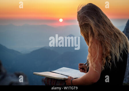 Jeune femme au sommet, écrit dans un livre, Scheffauer, Wilder Kaiser, Tyrol, Autriche Banque D'Images
