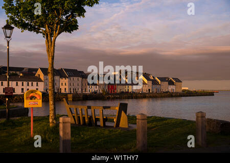 Le coucher de soleil peint le ciel au-dessus de la célèbre rose longue marche avec sa rangée de belles maisons colorées situé au port de Corrib, Galway, comté de Galw Banque D'Images