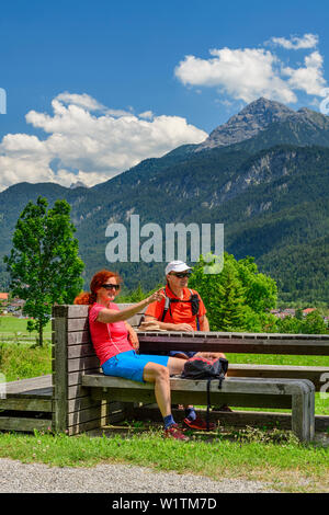 Homme et femme assis sur un banc et avoir une pause, Alpes de Lechtal en arrière-plan, Weissenbach, Lechweg, vallée de Lech, dans le Tyrol, Autriche Banque D'Images