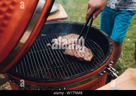 Close-up homme part pièce de viande juteuse grillés au barbecue high angle Banque D'Images