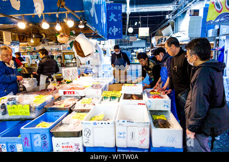 Les gens qui achètent des fruits de vendeurs au marché aux poissons de Tsukiji à Tokyo, Japon Banque D'Images
