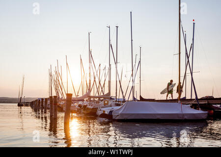 Les gens sur une jetée au coucher du soleil au lac Ammersee, Bavaria, Germany, Europe Banque D'Images